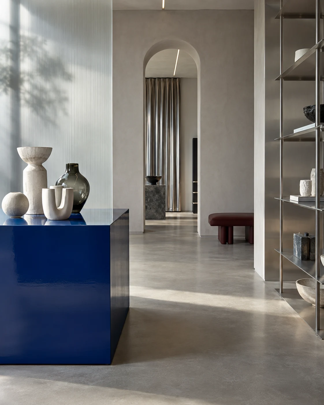 Concept showroom with a blue display plinth, ceramics and brushed steel shelving